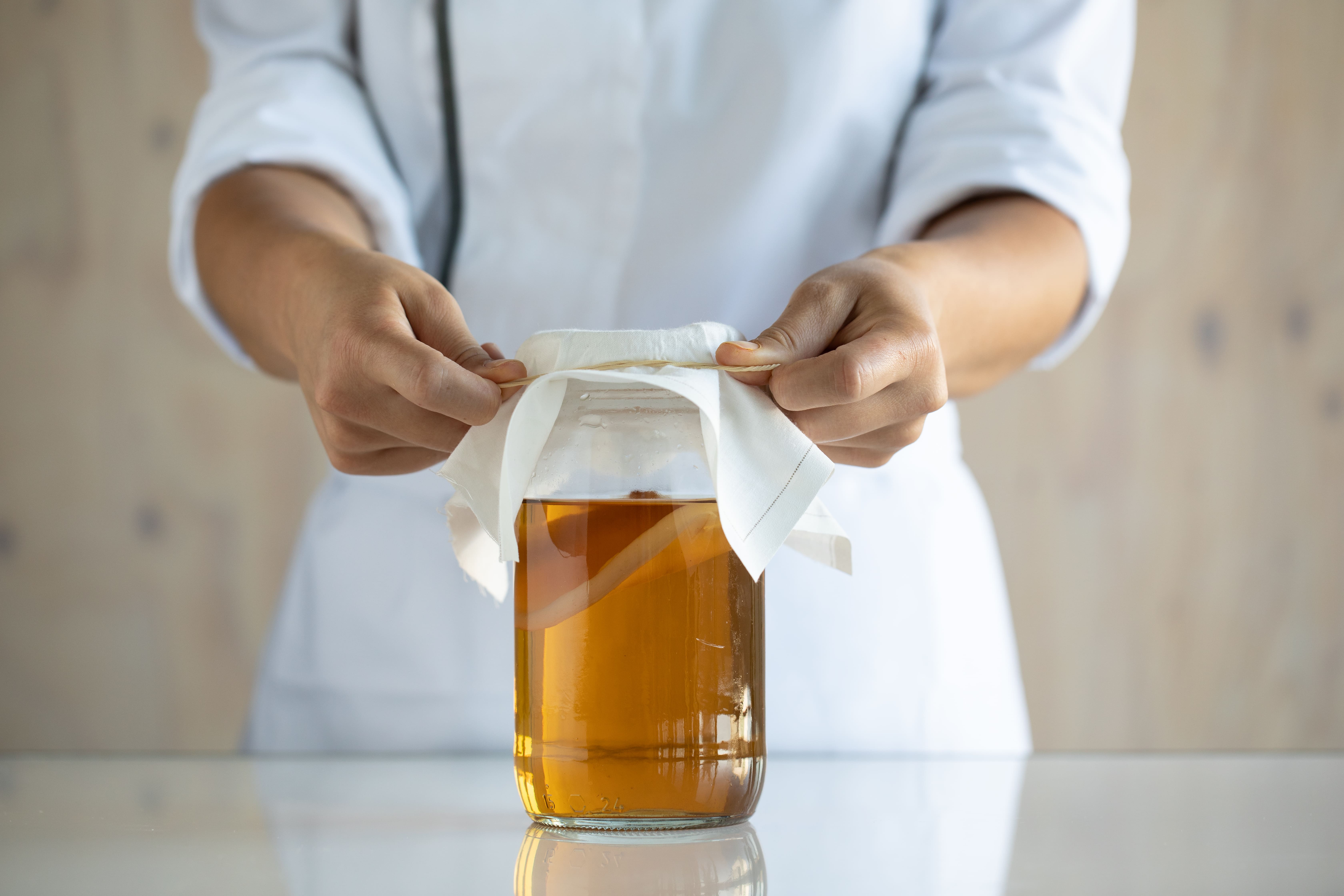 Una persona cerrando un bote de líquido fermentado